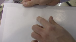 The crap used glass has a white piece of paper over the backside of it. This is not factory applied, this is applied by a person - a lowly skilled one at that, who often eats over his work. You'll find dust and all sorts of crap between this piece of paper and the glass, as it is not sealed.