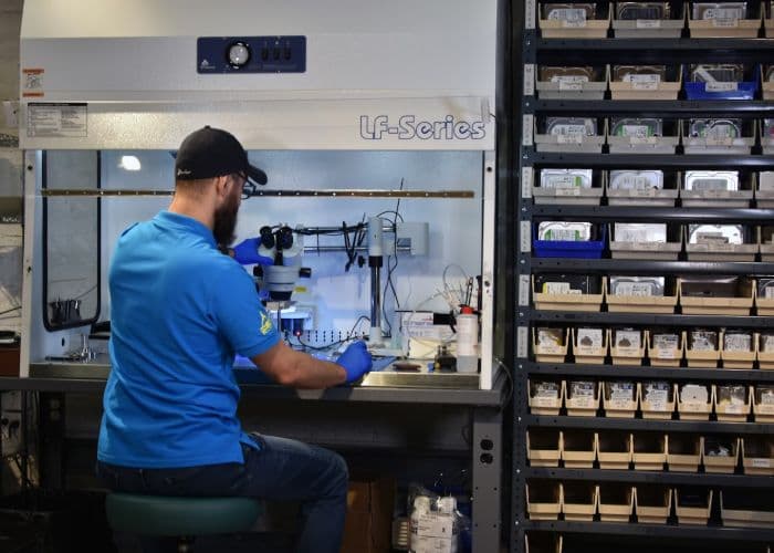 Technician performing hard drive recovery at the laminar flow bench with microscope and donor drive inventory